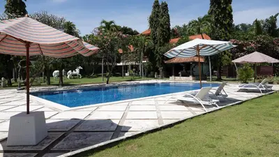 a swimming pool with two umbrellas and two chairs at Bali Bungalo Hotel in Kuta