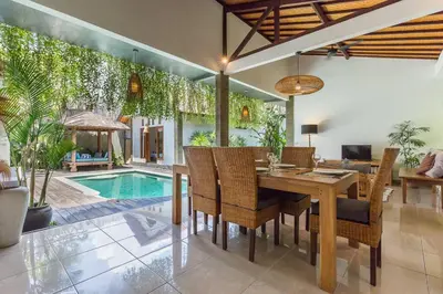 a dining room with a table and chairs and a pool at Pulesari 3 bedrooms in Seminyak