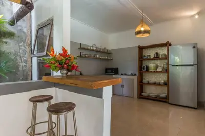 a kitchen with a counter with stools and a refrigerator at Pulesari 3 bedrooms in Seminyak