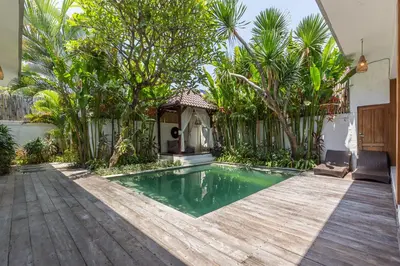 a backyard pool with a wooden deck and a gazebo at Pulesari 2 bedrooms in Seminyak