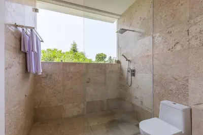 a bathroom with a toilet and a glass shower at Villa Lansel in Seminyak