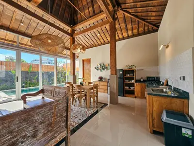 a kitchen with wooden ceilings and a dining room at Svarna Suites Seminyak in Seminyak