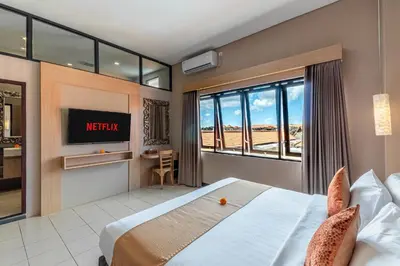 a hotel room with a bed and a tv at Svarna Suites Seminyak in Seminyak