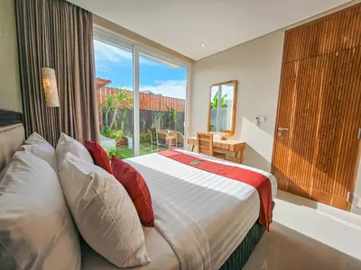 a bedroom with a bed and a large window at Svarna Suites Seminyak in Seminyak
