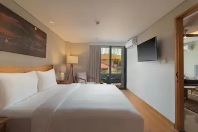 a bedroom with a large white bed and a tv at Beachwalk Residence in Kuta