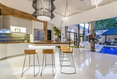 an open kitchen with a bar and stools at Villa Lora in Seminyak