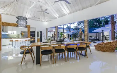 an open kitchen and dining room with a wooden table and chairs at Villa Lora in Seminyak