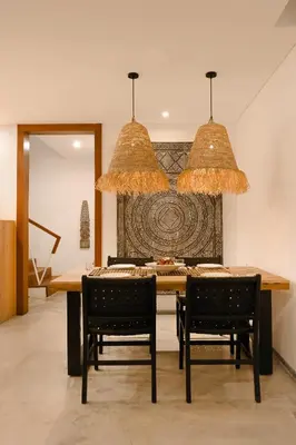 a dining room with a table and chairs and two lights at Cascata Villa Canggu in Canggu
