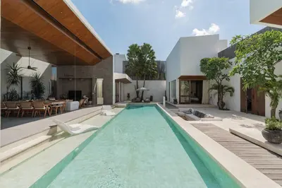 an outdoor swimming pool with chairs and a house at Villa Boya - 6BR luxury oasis in Central Berawa in Canggu