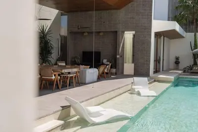 a swimming pool with chairs and a table and a house at Villa Boya - 6BR luxury oasis in Central Berawa in Canggu