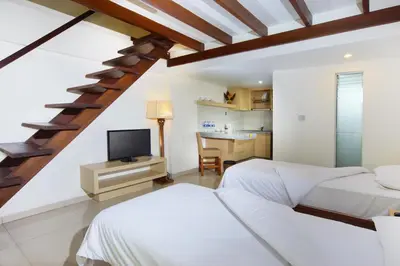 a attic bedroom with two beds and a television at The Legian Sunset Residence in Seminyak