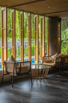 a lobby with chairs and a table and windows at Kayumas Seminyak Resort in Seminyak