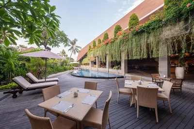 a patio with tables and chairs and a swimming pool at Kayumas Seminyak Resort in Seminyak