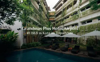 a hotel with a swimming pool in front of a building at Grandmas Plus Hotel Airport in Kuta