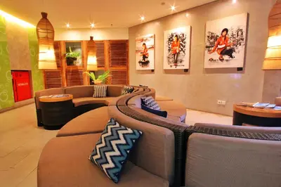 a living room with couches and tables and posters on the wall at Grandmas Plus Hotel Airport in Kuta