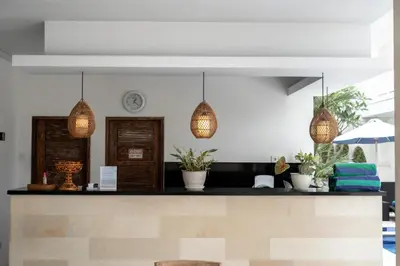 a lobby with a counter with potted plants and lights at The Eight Villa & Rooms Bali - Seminyak in Seminyak