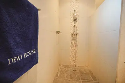 a bathroom with a shower with a clock on the wall at Villa Dewi in Seminyak