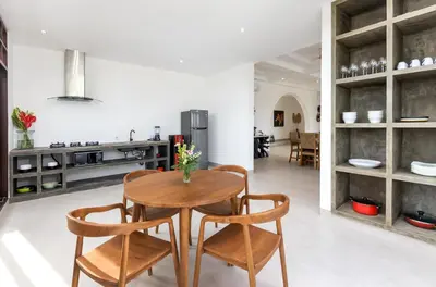 a kitchen and dining room with a wooden table and chairs at Villa Besakih in Canggu
