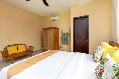 a bedroom with a large bed and a chair at Villa Besakih in Canggu