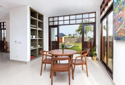 a dining room with a wooden table and chairs at Villa Besakih in Canggu