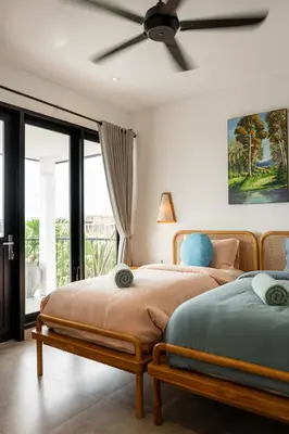 two beds in a bedroom with a ceiling fan at Villa Sakayana 4BR Canggu in Canggu