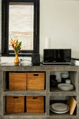 a kitchen with a counter with a microwave and plates at Villa Sakayana 4BR Canggu in Canggu
