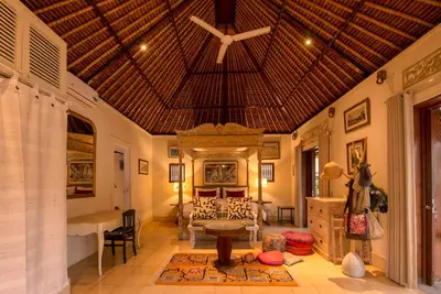 a large room with a bed and a ceiling at Bebek Cottages Sanur in Sanur