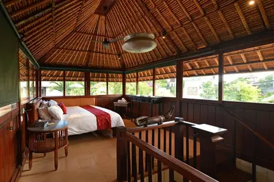 a bedroom with a bed in a room with windows at Bebek Cottages Sanur in Sanur