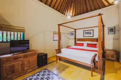 a bedroom with a bed and a flat screen tv at Bebek Cottages Sanur in Sanur