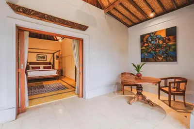 a room with a table and a bedroom at Bebek Cottages Sanur in Sanur