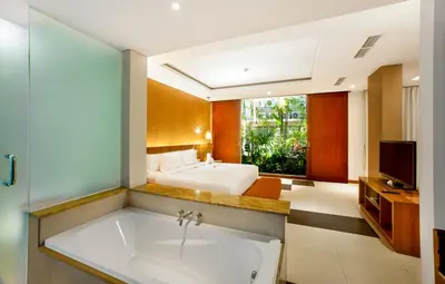 a bathroom with a sink and a bed and a television at Sun Island Hotel & Spa Legian in Legian