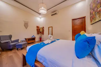 a bedroom with a large bed and a chair at Villa Paradise Seminyak in Seminyak