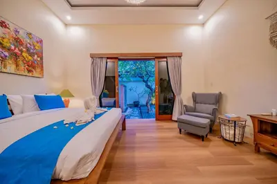 a bedroom with a bed and a chair and a window at Villa Paradise Seminyak in Seminyak