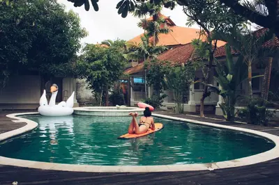 two people on a paddle board in a pool with swans at Endless Summer Surf Camp Kuta in Kuta