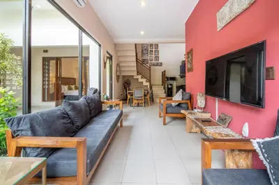 a living room with a couch and a red wall at Villa Kinawa Seminyak in Seminyak
