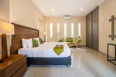 a bedroom with a large bed and a couch at Villa Kinawa Seminyak in Seminyak