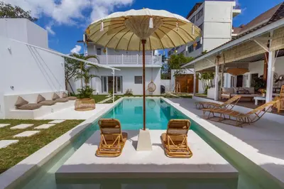 an outdoor swimming pool with chairs and an umbrella at Villa M2 Seminyak by Alfred in Bali in Seminyak