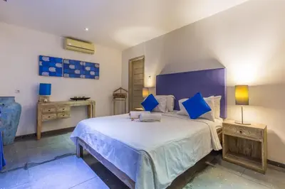 a bedroom with a large bed with blue pillows at VILLA Nuri Merah 2 in Seminyak
