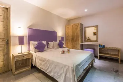a bedroom with a large bed with purple pillows at VILLA Nuri Merah 2 in Seminyak
