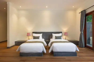 two beds in a room with two lamps at Andaman Umalas by Kerta Living in Canggu