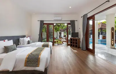 two beds in a hotel room with a pool at Andaman Umalas by Kerta Living in Canggu
