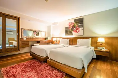 a large bedroom with two beds and a red rug at Pandawa All Suites Hotel in Seminyak