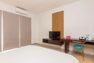 a room with a bed and a desk and a television at Mi Casa Residence in Seminyak