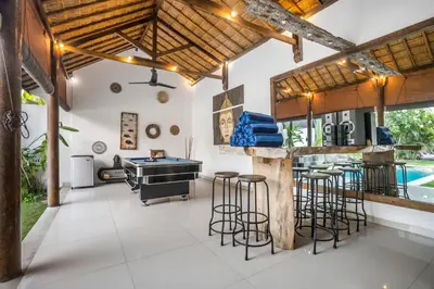 an outdoor kitchen with a bar and stools at Villa Baik Baik by BaliSuperHost in Seminyak