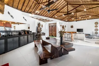 a kitchen with a wooden table and a statue at Villa Baik Baik by BaliSuperHost in Seminyak