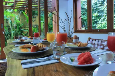 a wooden table topped with plates of food and fruit at Papillon Umalas Villas in Canggu