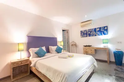 a bedroom with a large white bed with blue pillows at Villa Jalak in Seminyak