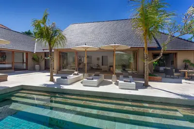 a villa with a swimming pool and palm trees at Balidroomvilla Sanur - Full Serviced - Beachside in Sanur