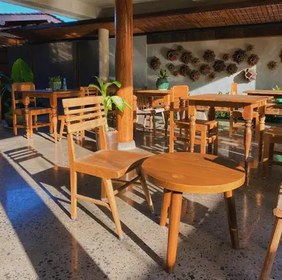 a group of wooden tables and chairs in a restaurant at Tekuni 2 in Legian
