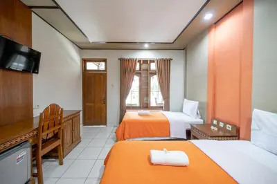 a hotel room with two beds and a television at Bendesa Accommodation in Kuta